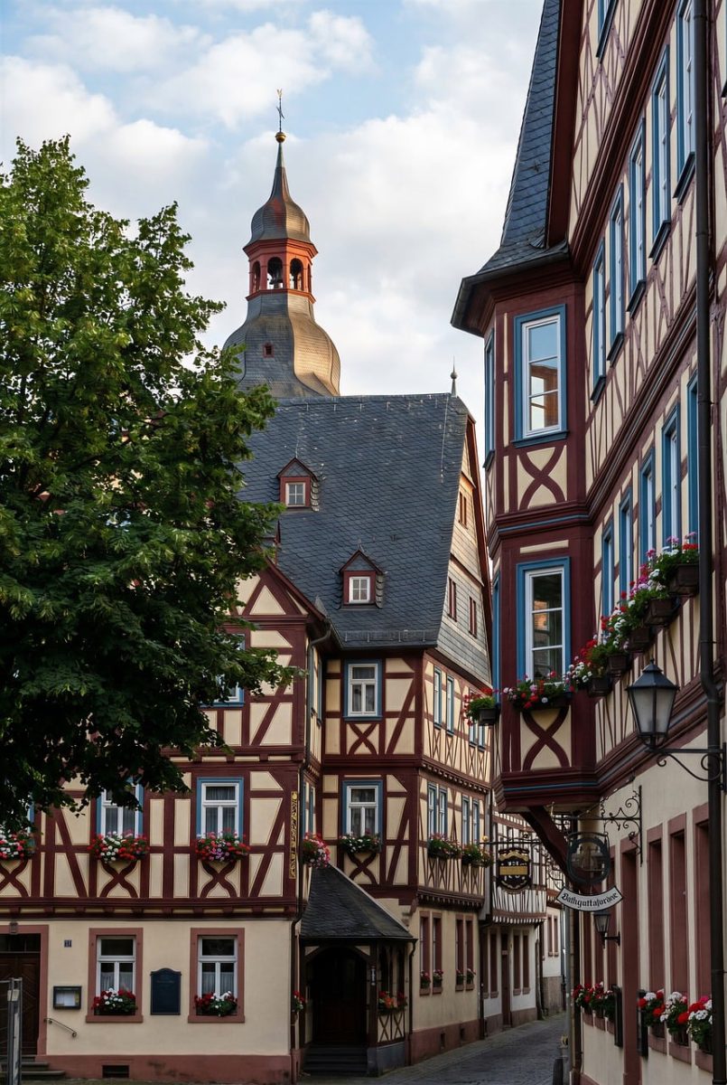 half-timbered house, historic architecture, cityscape, european village, church tower, traditional architecture, city street, romantic place, late afternoon, medieval style, flower boxes, wooden stucco, fresh flowers, window with flowers, red and white house, historic town, floral decoration, town center, pleasant afternoon, memorable place