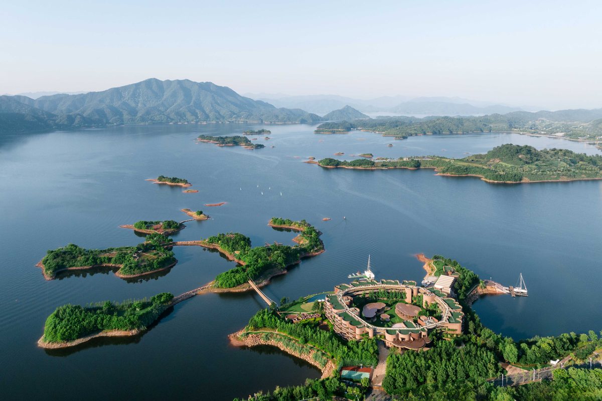 lake, aerial view, island, resort, green, mountains, peaceful, tourist attraction, vacation, water body, cruise ship, coastline, nature, hiking, relaxation, luxury accommodation, clear sky, geographic beauty, ecotourism