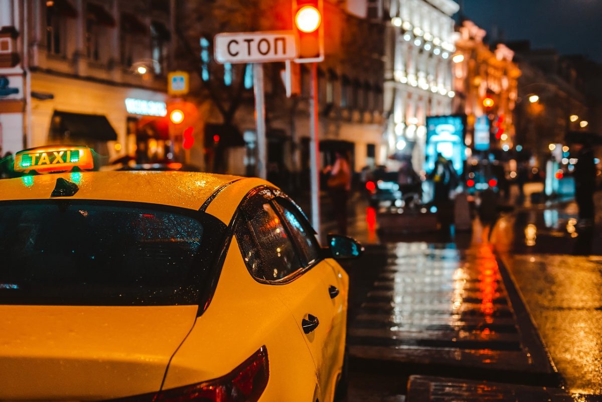taxi, city at night, traffic signal, yellow, lighting, rainy, street, nighttime, vehicle, rainy evening, stop sign, square, red light, stop traffic, reflective surface, traffic jam, sidewalk, raindrops, urban traffic, evening city