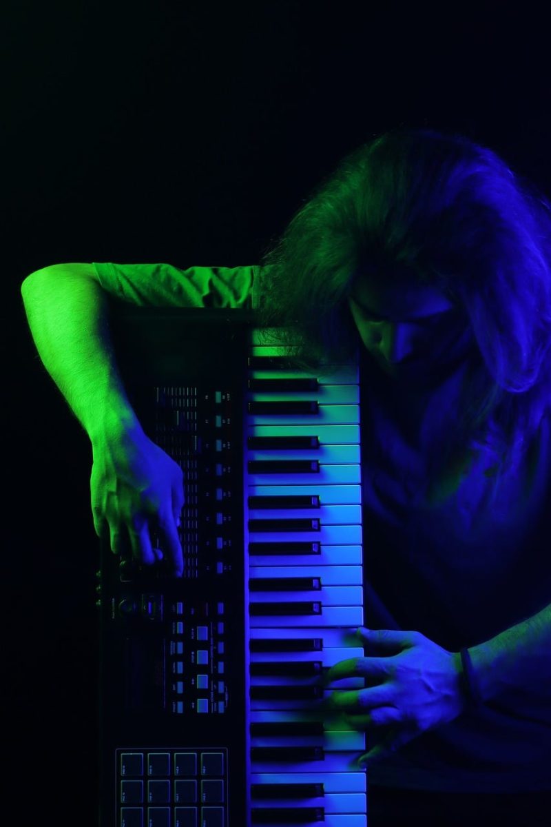 man, musician, keyboard, colorful lighting, blue light, purple light, dark background, dramatic lighting, studio, creative lighting, photography, art, moody, musician portrait, male portrait, blue and purple, musical instrument, emotive, pose