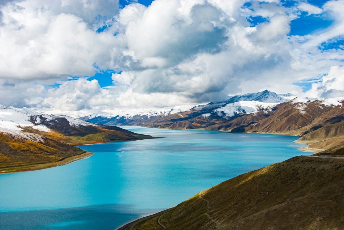 yamdrok lake, tibet, sacred lake, turquoise water, mountain landscape, snow-capped mountains, high altitude, untouched nature, cumulus clouds, mountain road, nature, tibetan plateau, scenery, water, natural beauty, blue sky, view, alpine scenery, natural wonder, tourist attraction