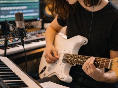 female musician, electric guitar, home studio, recording studio, music production, songwriting, music creation, keyboard, digital audio workstation, studio equipment, microphone, headphones, audio recording, sound engineer, creative process, musician workspace, modern studio, audio editing, vertical composition, musical instrument