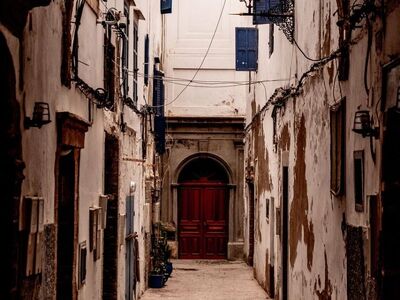 morocco, essaouira, architecture, old alley, wooden door, blue shutters, stone path, street lamp, window, grand arch, city alley, historic building, romantic view, historical quarter, narrow architecture, street charm, eye for architecture, rocky urban terrain, completely deserted