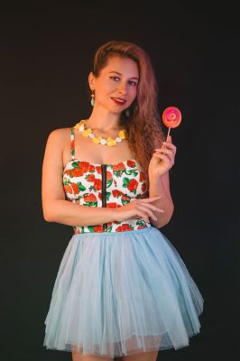 woman, portrait, model, posing, blonde hair, style, fashion, lollipop, summer dress, earrings, bracelet, smile, dancer, black background, necklace, stone, red color, yellow color, floral pattern, contemporary fashion, trend