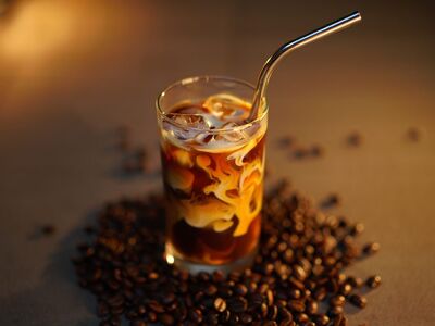 iced coffee, metal straw, ice, coffee, milk, espresso, cold drink, coffee beans, dark background, moody lighting, coffee and milk, glass, swirling milk, coffee brewing art, coffee shop, slow motion, close-up, comfort drink, elegant look, toward plastic bans