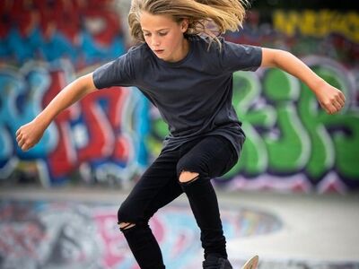 skateboarding, skateboard trick, teen skateboarder, extreme sports, balance and coordination, graffiti wall, urban culture, outdoor recreation, creative expression, adolescent athlete, long hair, youth sports, action photography, youthful, city sport, teen boy, alternative lifestyle, youth fashion, motion and movement, skateboard lifestyle
