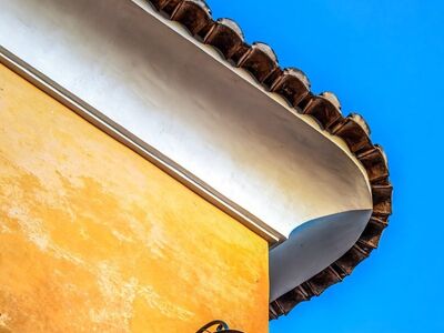 facade, architecture, lamp, outdoor lighting, blue sky, yellow, ornamentation, corner, light, aesthetic, edge, corner decoration, vertical lines, height details, yellow-orange facade, ornamental corner, outdoor architecture, classic style, aesthetic facade