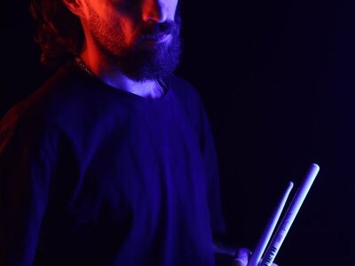 portrait, musician, drummer, drumsticks, blue light, purple light, dark background, dramatic lighting, creative photography, artist, creative portrait, studio portrait, persian, male, moody, colorful lighting, musician portrait, cinematic, studio