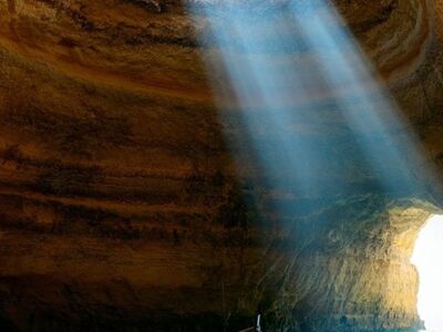 cave, natural light, beach, sun rays, boat, shallow water, sand, sea, rock formation, portugal, benagil, algarve, tourist attraction, nature, blue shade, hiking, reflecting light, view from cave, cozy atmosphere, ai generated