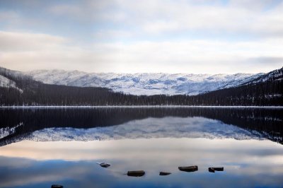 snow covered lake, mountain reflection, winter landscape, calm water, mist, soft light, cloudy sky, peaceful, tranquil, natural beauty, postcard, water reflection, peaceful landscape, snowy mountains, winter calm, afternoon light, meditative, calm lake, cloud reflection