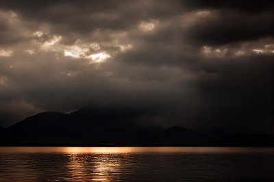 mountains, sunset, water surface, reflection, dark clouds, mountain silhouette, lake, landscape, calm, natural scenery, twilight, calm water, light effect, breathtaking, nature, evening, peace, relaxation